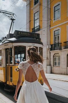 a woman in a white dress is walking down the street with a trolley behind her