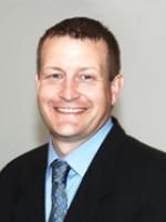 a man in a suit and tie smiling at the camera