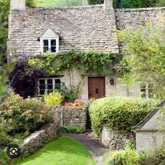 an old stone house surrounded by greenery and flowers