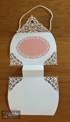 a white card with a pink doily on the front and back, sitting on a wooden table