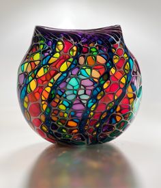 a colorful glass vase sitting on top of a table