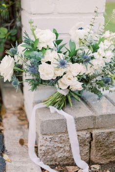 a bouquet of white flowers sitting on top of a cement block next to a brick wall