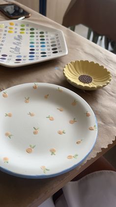 a white plate sitting on top of a table next to a remote control and a yellow flower