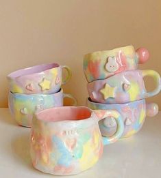 four ceramic mugs sitting on top of a white table next to each other and one has a teddy bear