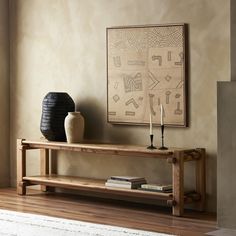 a wooden table sitting next to a vase on top of a hard wood floor in front of a painting