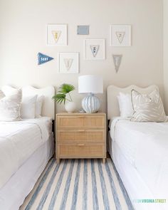 two beds in a bedroom with white walls and blue and white striped rug on the floor