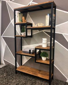 a shelving unit with wooden shelves and metal frame, in front of a geometric wall