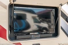 an rv with its door open and the television on it's side is reflected in the rear window