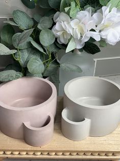 three vases sitting next to each other on a table with flowers in the background