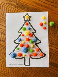 a paper christmas tree with pom poms on it