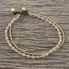 Thai artisan Tiraphan Hasub carefully chooses stones of natural rose quartz beading the length of this anklet. The beads are alternated with petite brass beads accompanied by a beaded strand of brass. The fashionable anklet is completed with two ringing brass bell buttons giving it an adjustable length. Diy Anklets, Bling Makeup, Christmas Beading, Rose Quartz Bracelet Beads, Diy Bling, Jewlery Necklace, Diy Beading, Beaded Jewelry Necklaces, Beaded Anklet