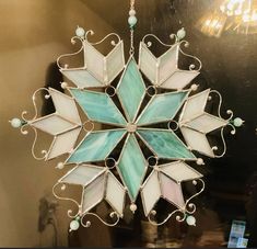 a glass snowflake hanging from a ceiling in a room with a cell phone on the wall