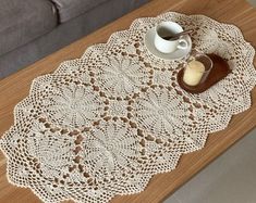 a coffee table with a doily next to a cup and saucer on it