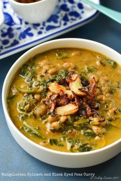 a bowl of soup with mushrooms and spinach in it on a blue tablecloth