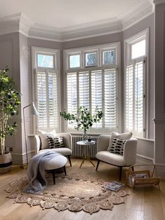 a living room filled with furniture and windows covered in white shuttered shades on top of them