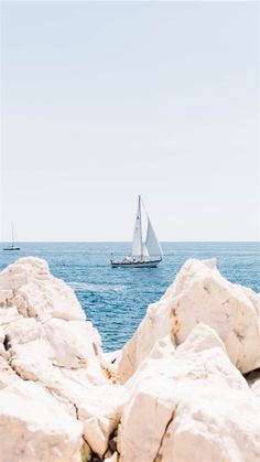 a sailboat in the ocean near some rocks