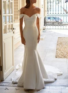 a woman in a white wedding dress is standing on the floor near an open door