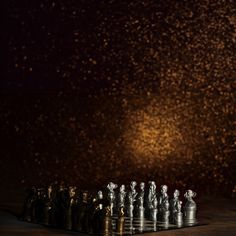 a set of chess pieces sitting on top of a wooden table in front of a dark background