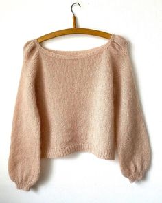 a pink sweater hanging on a wooden hanger