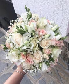 a bridal bouquet is being held by someone's hand on a cobblestone street