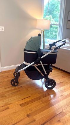 a baby stroller sitting on top of a hard wood floor next to a window