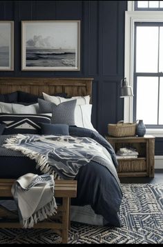 a bedroom with dark blue walls and bedding in the center, along with two framed pictures on the wall