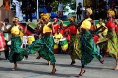 several women in brightly colored dresses dancing on the street