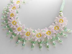 a necklace with flowers and green beads on a white background, in the shape of a circle