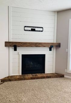 an empty living room with a fireplace and white walls