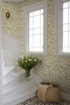 a vase with flowers sitting on top of a set of stairs next to a window