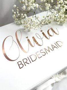 the bridesmaid sign is next to some flowers and white ribbon on a table