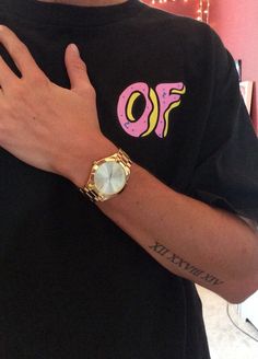 a person wearing a black shirt with a gold watch on their wrist