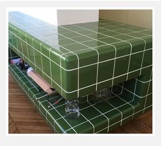 a green bench that has some cups on it and toothbrushes in the bottom drawer