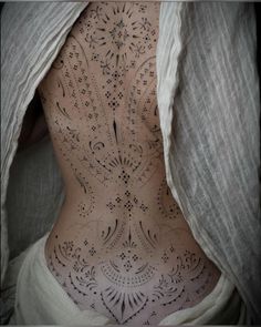 the back of a woman's body with intricate tattoos on her stomach and chest