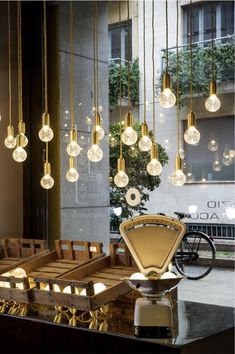 a bunch of lights hanging from the side of a building next to a table with chairs