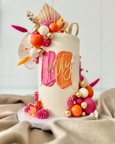 a white cake with pink, orange and gold decorations on it's side sitting on a table