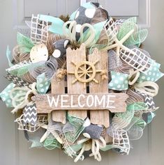 a welcome wreath is hanging on the front door with an anchor, wheel and ribbon