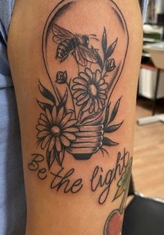 a woman's arm with a tattoo on it that says be the light and flowers