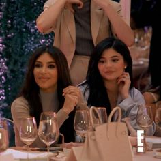 two women sitting at a table with wine glasses