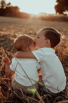 two babies are sitting in the middle of a field kissing each other with their heads touching