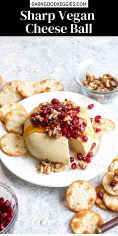 cheese ball with crackers and cranberries on a white plate next to other appetizers