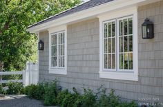 a house that has some windows on the side of it and bushes in front of it