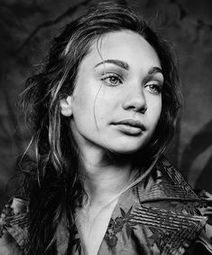 a black and white photo of a woman with long hair looking at the camera while wearing a shirt