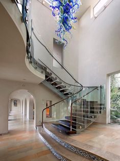 an elegant staircase with glass railings and blue flowers