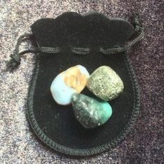 three stones in a pouch on the ground next to a black bag with zippers