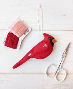 a pair of scissors next to a red bird ornament on a white table