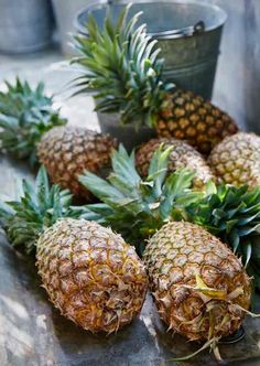 several pineapples sitting on a table next to a bucket