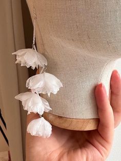 a hand is holding a white flower on a mannequin