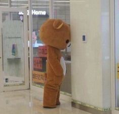 a person in a teddy bear costume leaning against a wall and looking at the ground