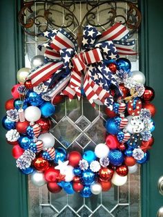 an american flag wreath is hanging on the front door with red, white and blue ornaments